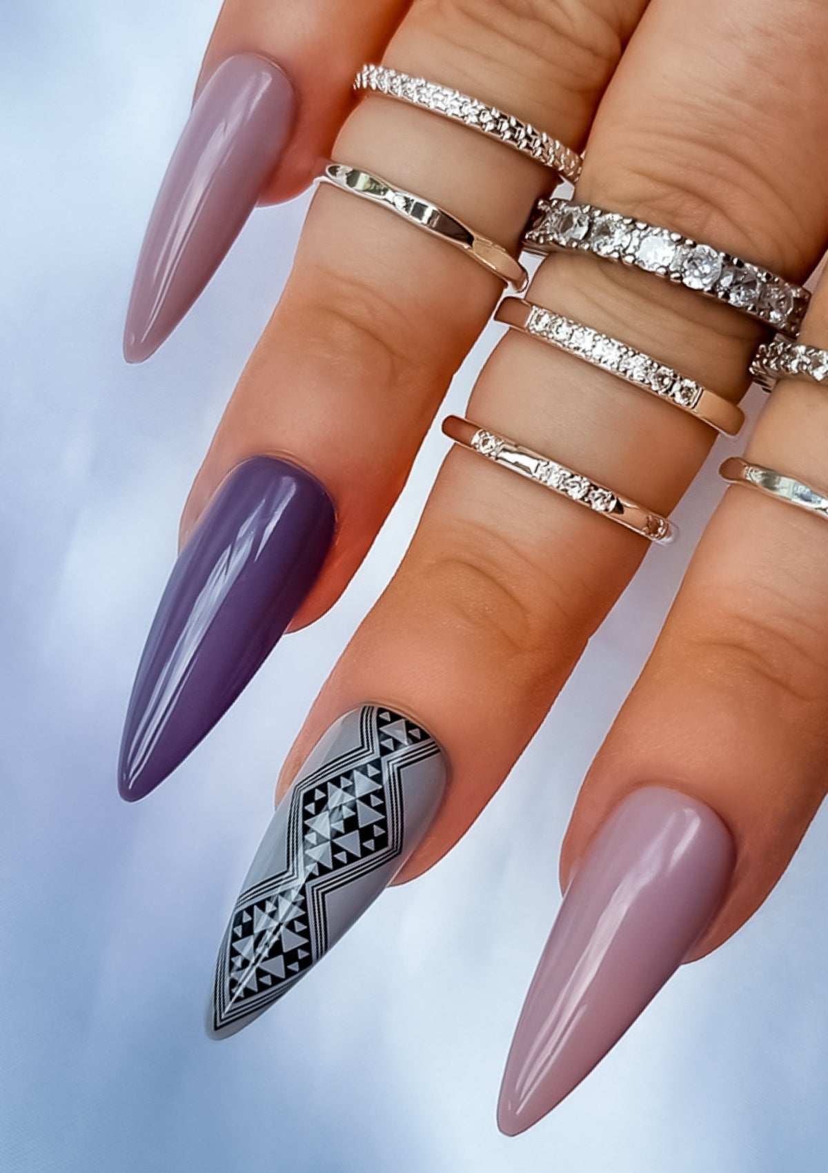 Long almond shaped nails in different shades of mauve and grey with black Maori nail art on the middle finger. Nail art design in Aonui pattern by Adrienne Whitewood.