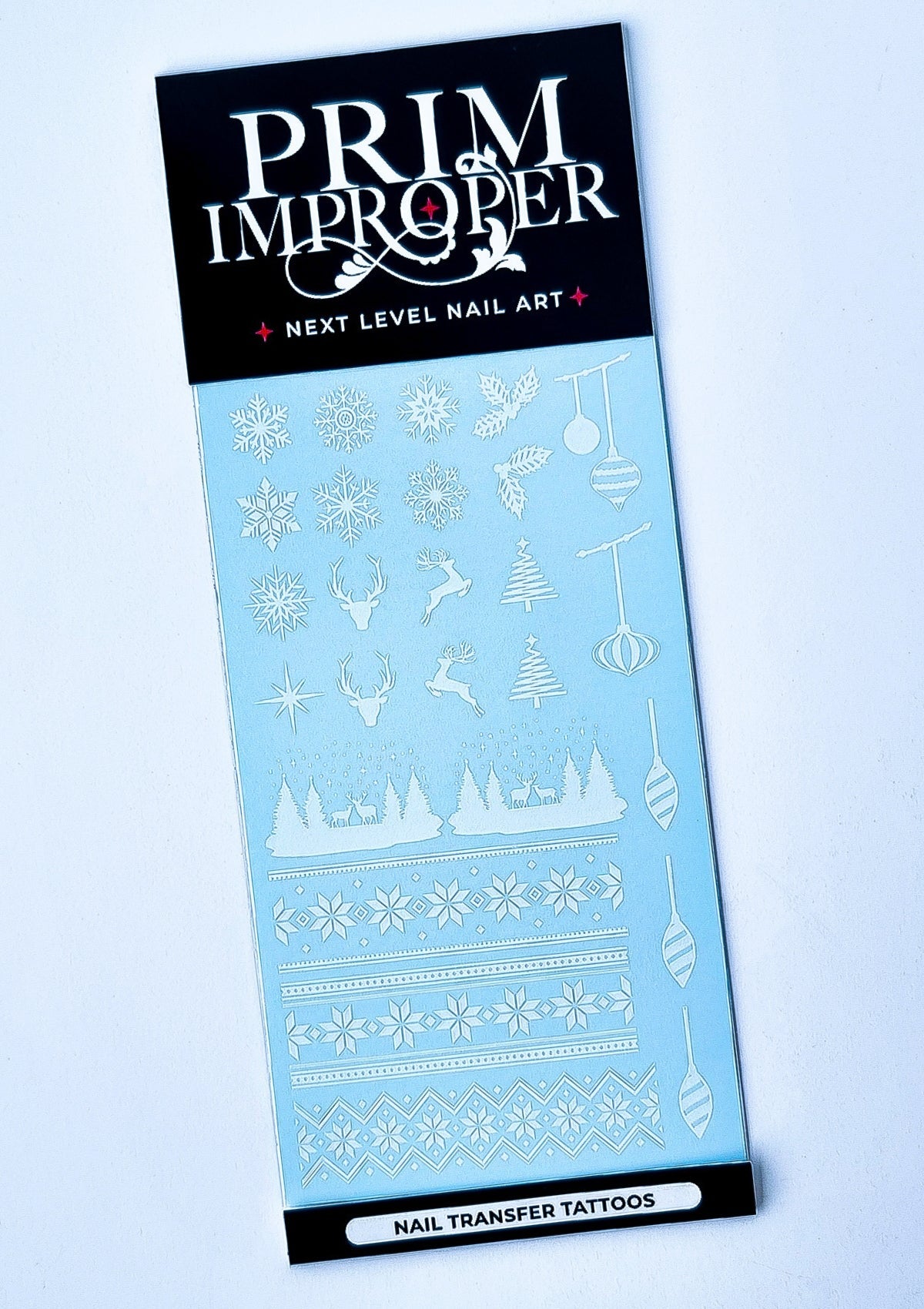 Sheet of white Christmas Nail Transfer Tattoos featuring Nordic sweater patterns, snowflakes, holly, reindeer, stars, Christmas trees and baubles